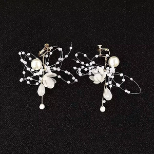 Detailansicht eleganter weißer Blumenohrringe mit Kunstperlen und goldenen Metallgliedern