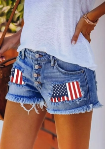 Detail of distressed denim shorts featuring American flag patches and frayed tassel hems