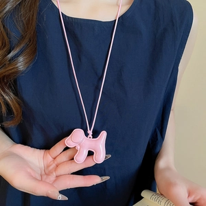 Détail d'un collier pendentif chien rose porté sur un fond de tissu bleu marine