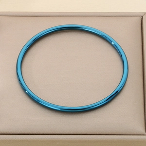 Detail view of a 3mm blue stainless steel bangle placed inside a beige jewelry box