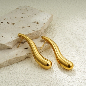 Detailed view of polished 18K gold waterdrop earrings resting on marble stone