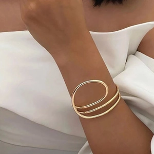 Detail shot of a minimalist gold triple-layer wrap bracelet on a model's wrist
