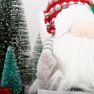 Close-up of knit Christmas gnome with red diamond pattern hat and white plush beard