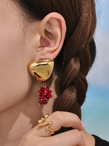 Close-up of geometric gold triangle earrings with red beads and matching wave ring