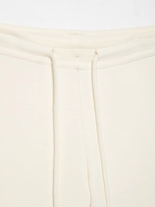 Détail de la taille à cordon blanc crème et du tissu en maille texturé du pantalon