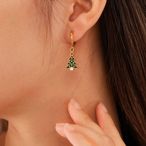 Detailed close-up of a Christmas tree earring with green enamel on a gold hoop