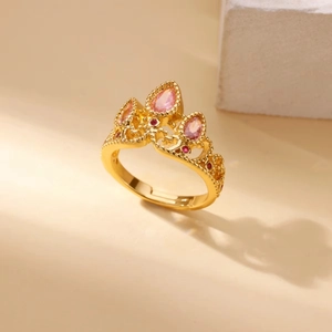 Macro view of golden crown ring featuring pink teardrop and red round zircon stones
