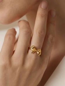 Elegant gold-plated bow ring on model finger showing brushed texture and luxurious style