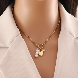 Collana dorata con ciondoli a cuore e fiori, perle e strass indossata dal modello