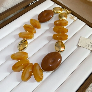 Detail of acrylic irregular necklace with brown and yellow resin beads and gold accents
