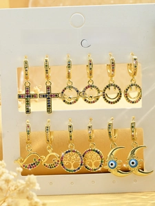 Detailed close-up of 6 pairs of gold earrings with zircon cross and planet charms