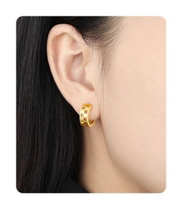 Close-up of a model wearing gold hollow checkered earrings in matte brushed silver