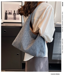Side view of large denim tote bag with brown leather straps worn by a model