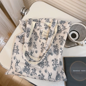 Detail of eco-friendly canvas tote bag showing blue rabbit print and woven label