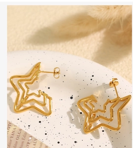Macro shot of layered gold star-shaped earrings on white ceramic plate decoration