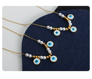 Detailed view of gold plated necklaces with evil eye pendants and white faux pearls