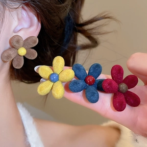 Close-up of colorful flocked flower stud earrings showing soft texture and petal details