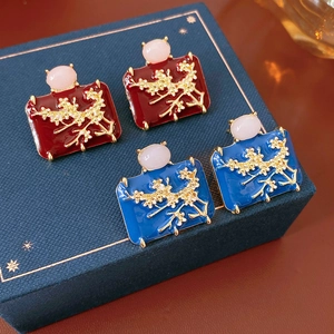 Detail of vintage enamel earrings with golden floral patterns and pink gemstone inlay