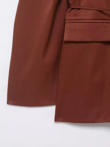 Detail of caramel blazer showing fine twill fabric texture, pocket flap and matching belt