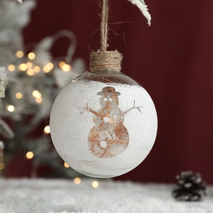 Transparent Christmas glass ball with snowman pattern and hay filler on red background