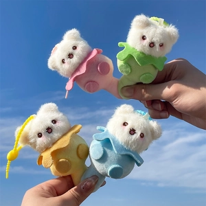 Close-up of four colorful plush bear keychains held against a bright blue sky background