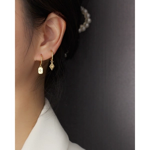 Detailed view of asymmetric gold starburst earrings worn by a model in office attire