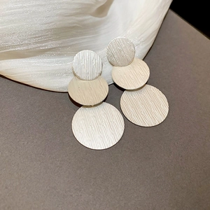 Detail of geometric triple disc earrings with a modern brushed vertical texture finish
