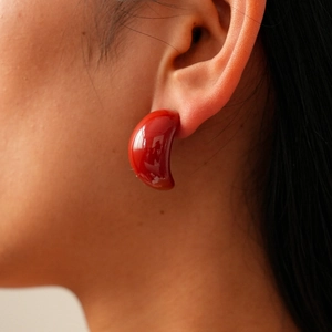 Detail showing high-gloss dark red bean-shaped earring with elegant drop design