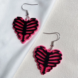 Pink and black acrylic heart ribcage earrings on white silk for Halloween style