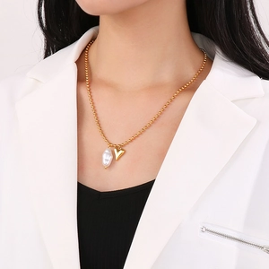 Minimalist gold beaded necklace with baroque pearl and 3D heart pendant worn by model