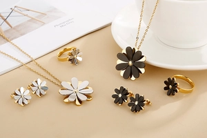 Detailed close-up of layered daisy flower jewelry set in gold, silver, and black finish
