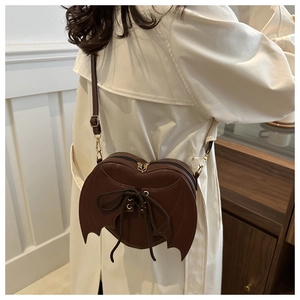 Dettaglio borsa a cuore marrone scuro con ali di pipistrello e stile gotico chic