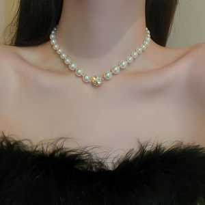 Gros plan d'un collier de perles vintage français avec un pendentif boule doré serti de strass