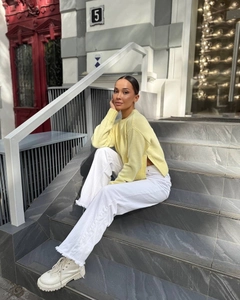 Detail of light yellow knit sweater with split hem paired with white wide-leg jeans