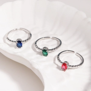 Adjustable silver ring with oval stones in blue green and red set in a white shell bowl