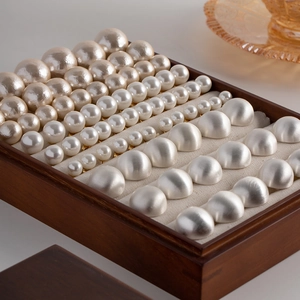 Brushed silver sphere and pearl stud earring set in different sizes on wooden box