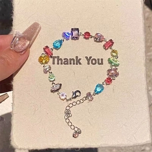 Macro detail of colorful mixed-cut cubic zirconia bracelet on a cream textured card