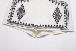 Close-up of white cotton linen shorts with ethnic geometric embroidery and detailed stitching