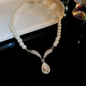 Detail of silver drop pearl necklace with rhinestone angel wings on a stylish dish
