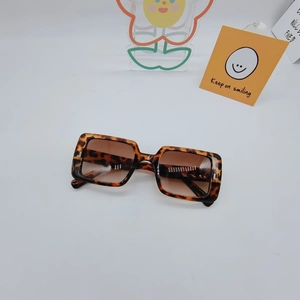 Close-up of leopard print square sunglasses with gradient lenses on a display stand