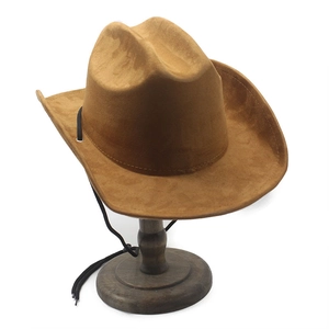 Close-up of camel faux suede western cowboy hat with black chin strap on a wood stand