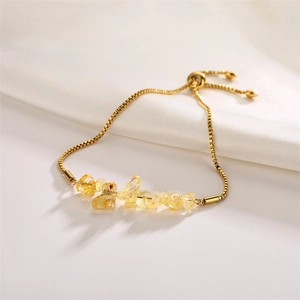 Adjustable gold chain bracelet featuring raw yellow natural crystal stones on white fabric