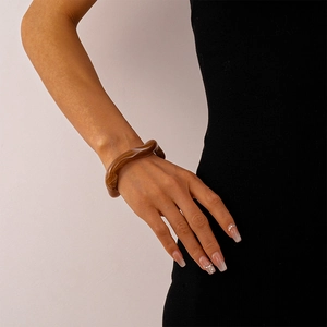 Close-up of brown acrylic resin wavy bangle featuring vintage marble amber texture patterns