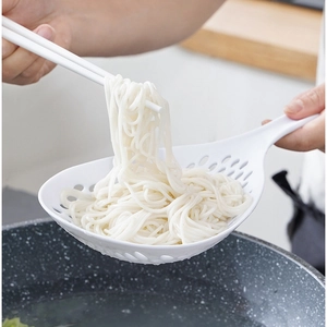 White long handle strainer scooping noodles in a kitchen, large capacity noodle skimmer