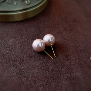Macro shot of pink pearls with golden posts on a brown velvet background jewelry detail