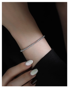 Close-up of minimalist silver bead bracelet worn by model showing metallic luster