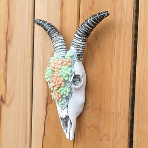 Floral sheep skull wall hanging with resin succulent decor on wooden texture background