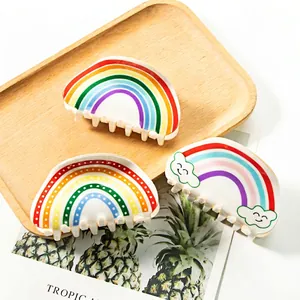 Three-piece rainbow claw clip set with cloud and dot patterns on a wooden tray