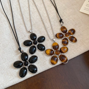 Detail view of vintage resin flower pendants with black onyx and tiger eye stones