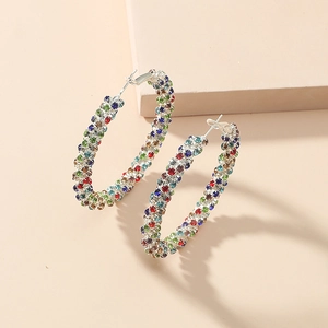 Macro detail of large silver hoop earrings featuring multi-color pavé set rhinestones